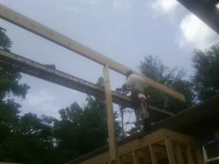 Carpenter setting a ridge beam over a new addition frame — Ice Dam Removal by Roofing Brothers in Bay Center