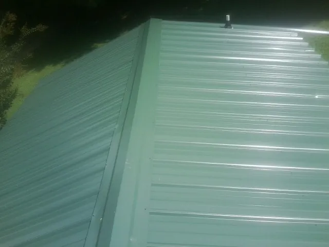 New green metal panels meeting at the ridge of a roof — Flat Roof Repair work by our crew in Bay Center