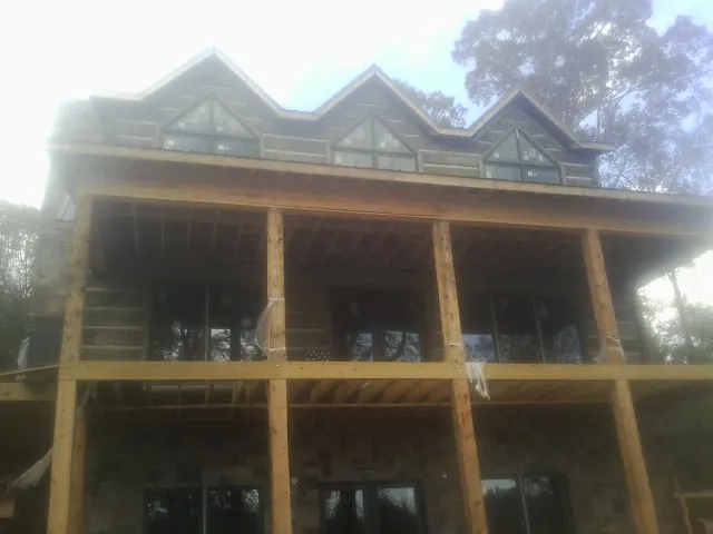 Dormers and porch framing on a large log home under construction — Roof Coating work by our crew in Bay Center
