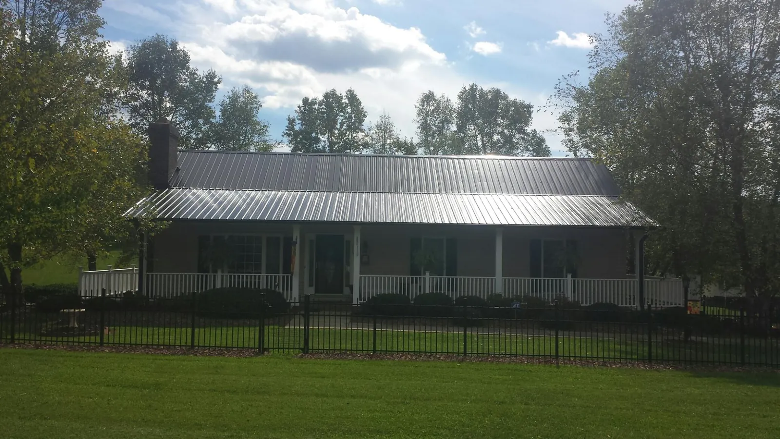 Gray metal roof on a brick ranch with a full width front porch — Gutter Guard Installation work by our crew in Bay Center