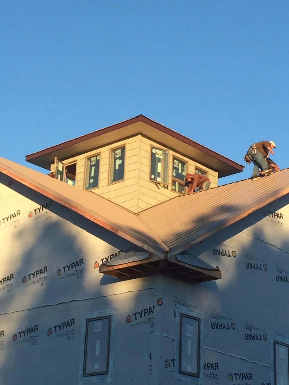 Roofers working around a rooftop cupola on a new metal roof at sunset — Roof Waterproofing in Bay Center by Roofing Brothers